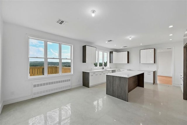 kitchen with sink, white cabinets, radiator, and a kitchen island