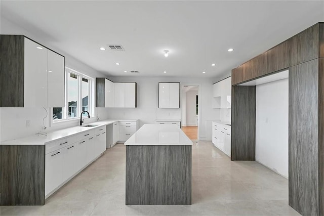 kitchen with a kitchen island, dark brown cabinets, white cabinets, and sink