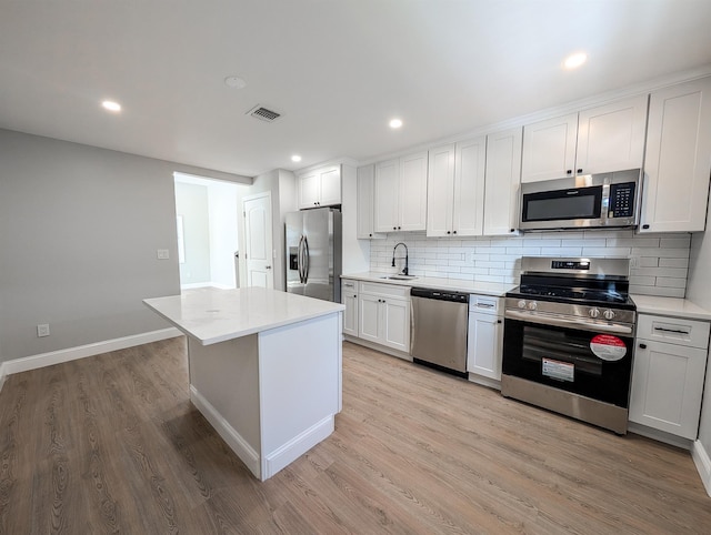 kitchen featuring light hardwood / wood-style flooring, sink, white cabinetry, a center island, and stainless steel appliances