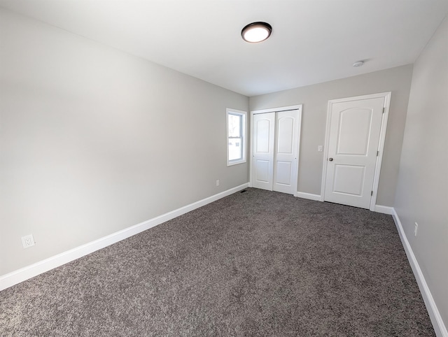 unfurnished bedroom featuring dark colored carpet and a closet