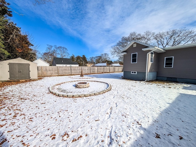 yard layered in snow featuring a fire pit and a storage unit