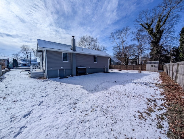 snow covered house featuring a storage unit