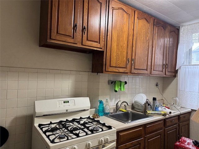 kitchen featuring sink, white gas range, and tasteful backsplash