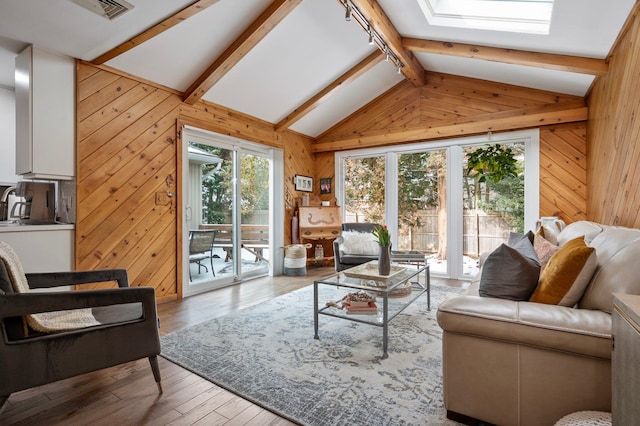 living room with light wood-type flooring, wooden walls, and lofted ceiling with skylight