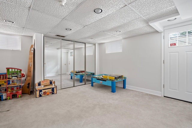 recreation room featuring a paneled ceiling and carpet flooring