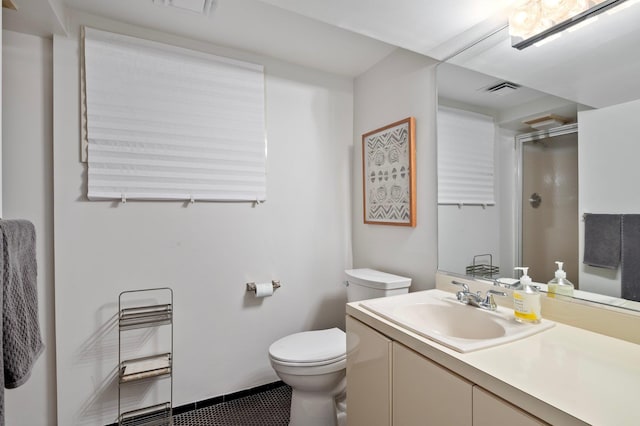 bathroom featuring a shower with shower door, toilet, and vanity