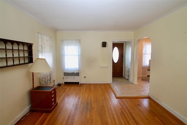 entryway featuring wood-type flooring, radiator heating unit, and ornamental molding