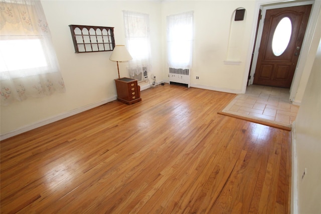 entryway with radiator heating unit, plenty of natural light, and light hardwood / wood-style floors