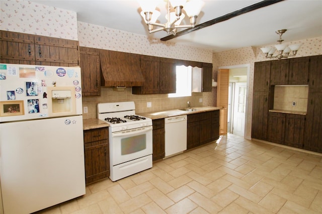 kitchen featuring custom exhaust hood, white appliances, decorative light fixtures, and a notable chandelier