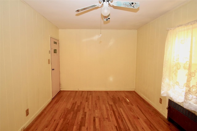 spare room with ceiling fan, hardwood / wood-style floors, and radiator heating unit