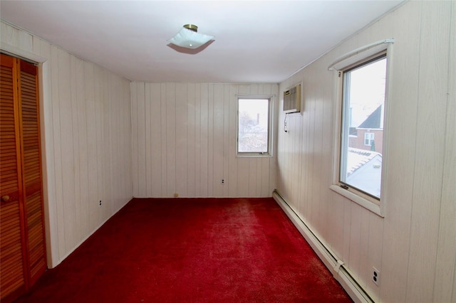 spare room with carpet floors, a baseboard radiator, wooden walls, and a wall mounted air conditioner