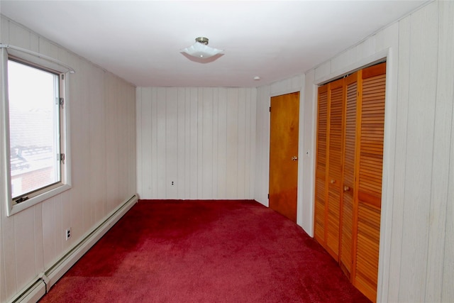 carpeted spare room featuring wooden walls, a wealth of natural light, and a baseboard heating unit