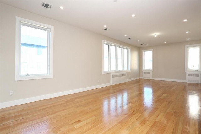 spare room featuring radiator heating unit and light wood-type flooring