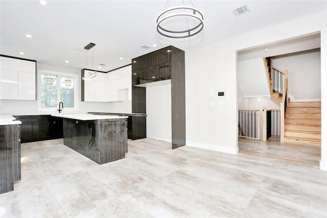 kitchen with a kitchen bar, white cabinets, a center island, and hanging light fixtures