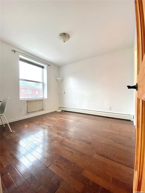 spare room with baseboard heating and dark wood-type flooring