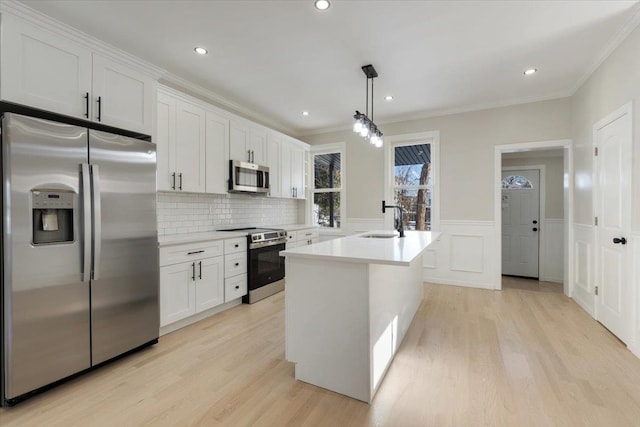 kitchen with white cabinets, stainless steel appliances, sink, and decorative light fixtures