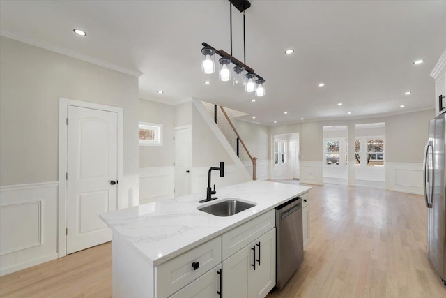 kitchen with white cabinetry, sink, decorative light fixtures, an island with sink, and stainless steel appliances