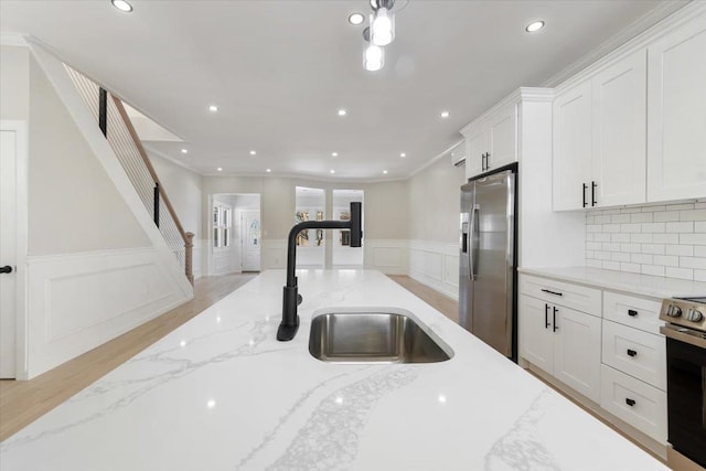 kitchen featuring sink, stainless steel appliances, white cabinetry, and light stone countertops