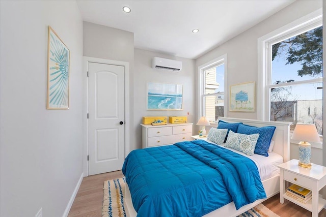 bedroom featuring a wall mounted AC and light hardwood / wood-style floors