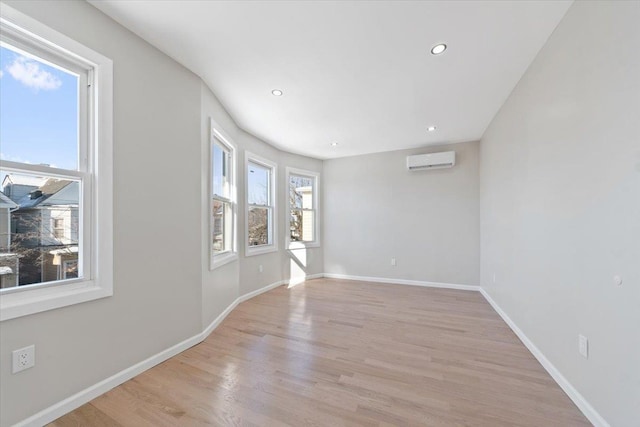 unfurnished room featuring light wood-type flooring and an AC wall unit