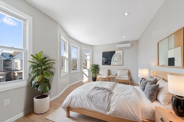 bedroom with multiple windows, a wall mounted air conditioner, and light wood-type flooring