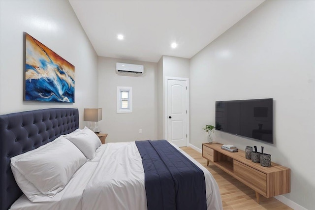 bedroom with a wall mounted AC and light hardwood / wood-style flooring