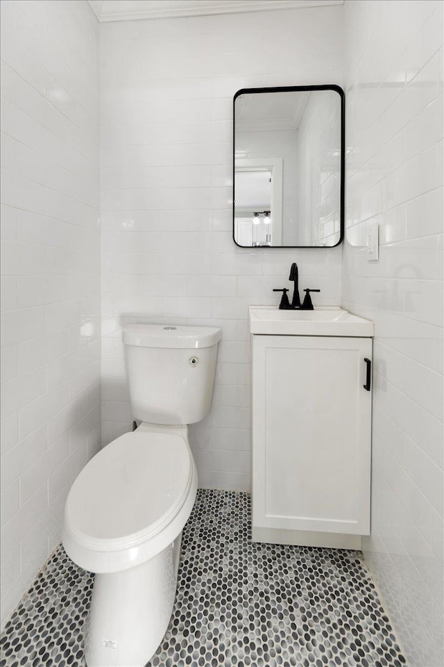 bathroom featuring vanity, toilet, crown molding, and tile walls