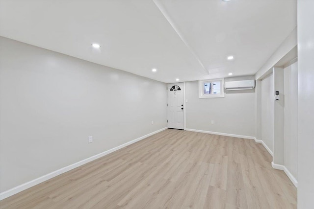 basement featuring light wood-type flooring and a wall unit AC