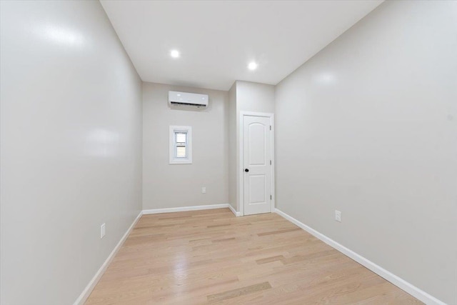 unfurnished room featuring a wall mounted air conditioner and light hardwood / wood-style floors