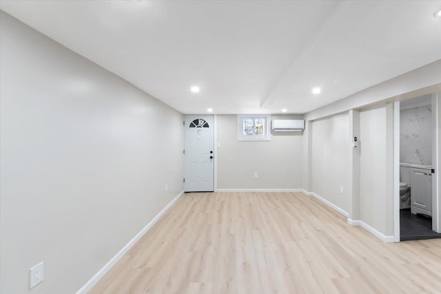 basement with a wall mounted air conditioner and light hardwood / wood-style floors