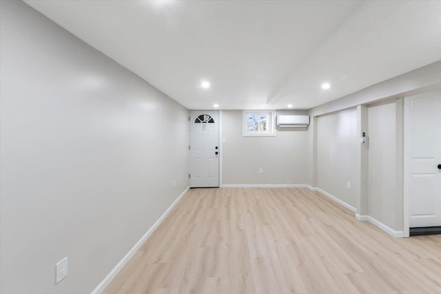 basement with light wood-type flooring and an AC wall unit