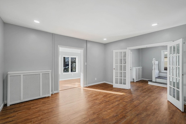 empty room featuring radiator heating unit, dark hardwood / wood-style flooring, and french doors