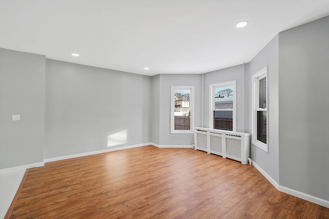 spare room featuring radiator heating unit and light hardwood / wood-style flooring