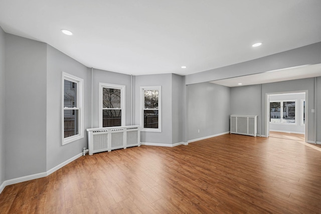 unfurnished living room with radiator heating unit and light hardwood / wood-style flooring