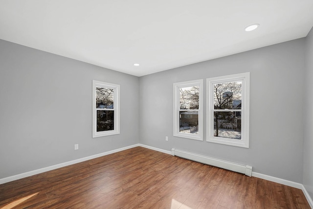 empty room featuring hardwood / wood-style floors and baseboard heating