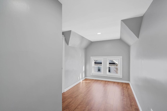 additional living space with vaulted ceiling and light hardwood / wood-style flooring