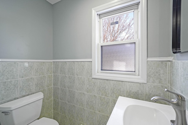 bathroom with sink, toilet, and tile walls