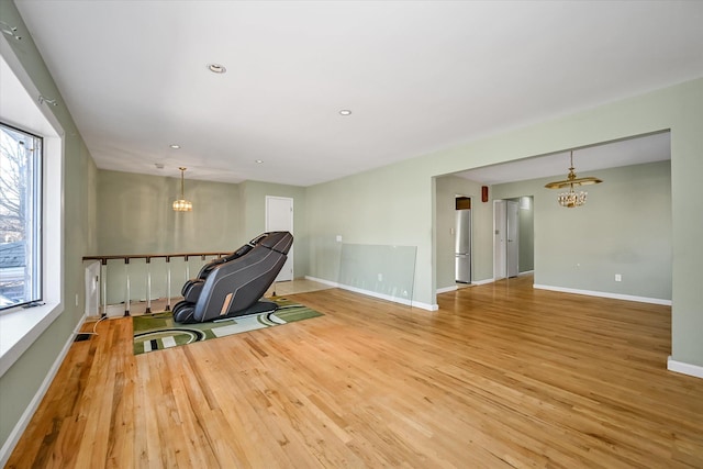 unfurnished room featuring a healthy amount of sunlight, a notable chandelier, and light wood-type flooring