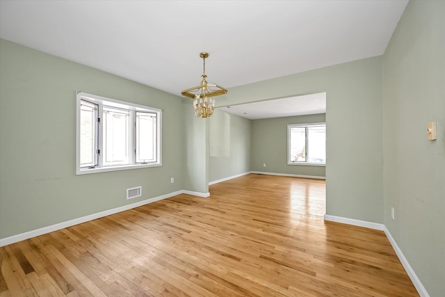 unfurnished room with light wood-type flooring and a notable chandelier