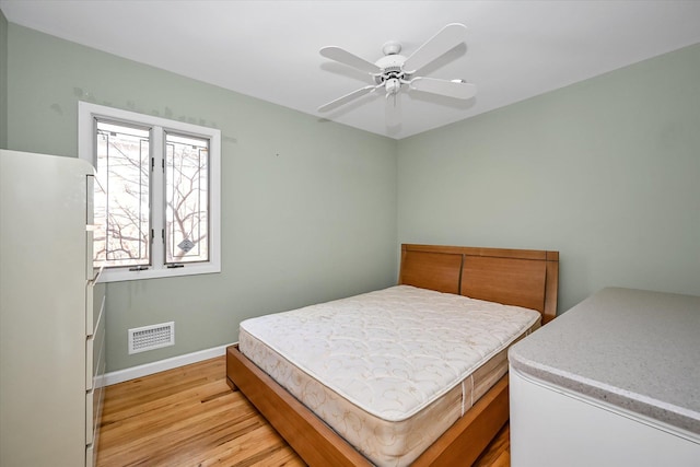 bedroom with white refrigerator, light hardwood / wood-style floors, and ceiling fan