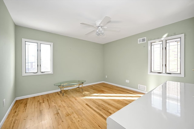 empty room with ceiling fan and light hardwood / wood-style flooring