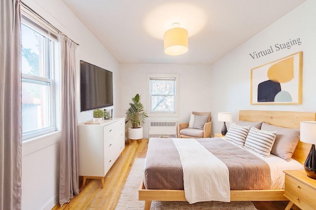 bedroom featuring light hardwood / wood-style floors, multiple windows, and radiator