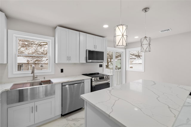 kitchen with stainless steel appliances, white cabinetry, light stone counters, and decorative light fixtures