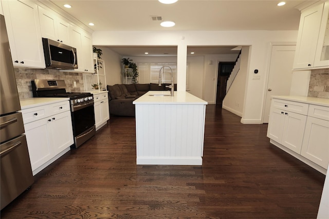 kitchen with sink, backsplash, appliances with stainless steel finishes, and a kitchen island with sink