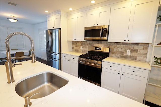 kitchen with sink, white cabinets, tasteful backsplash, and appliances with stainless steel finishes