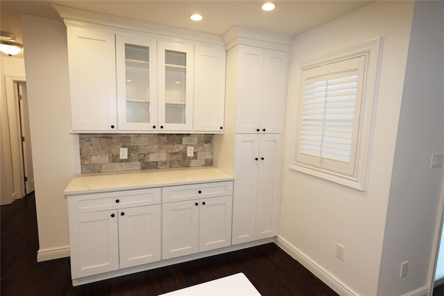 bar featuring backsplash, white cabinetry, and dark hardwood / wood-style flooring