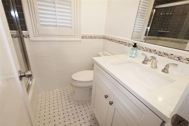 full bathroom with toilet, enclosed tub / shower combo, tile walls, tile patterned flooring, and vanity