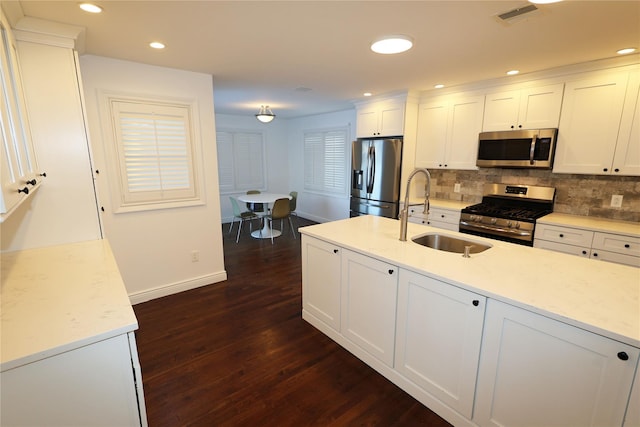 kitchen with appliances with stainless steel finishes, white cabinetry, sink, dark wood-type flooring, and light stone counters