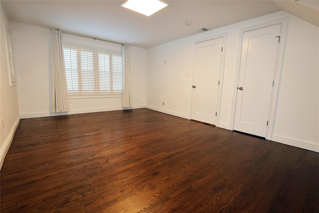 unfurnished bedroom with lofted ceiling and dark hardwood / wood-style flooring