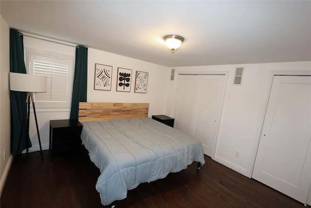 bedroom featuring multiple closets and dark hardwood / wood-style floors